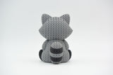 Detail shot of the crochet-style surface texture on a knitted raccoon ornament, showing the fine weave pattern