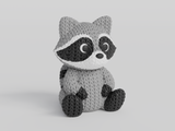 Close-up of a knitted raccoon figurine with a detailed crochet-look texture, shown against a white background