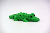Small knitted crocodile resting on a wooden shelf beside plants in a Scandinavian home interior
