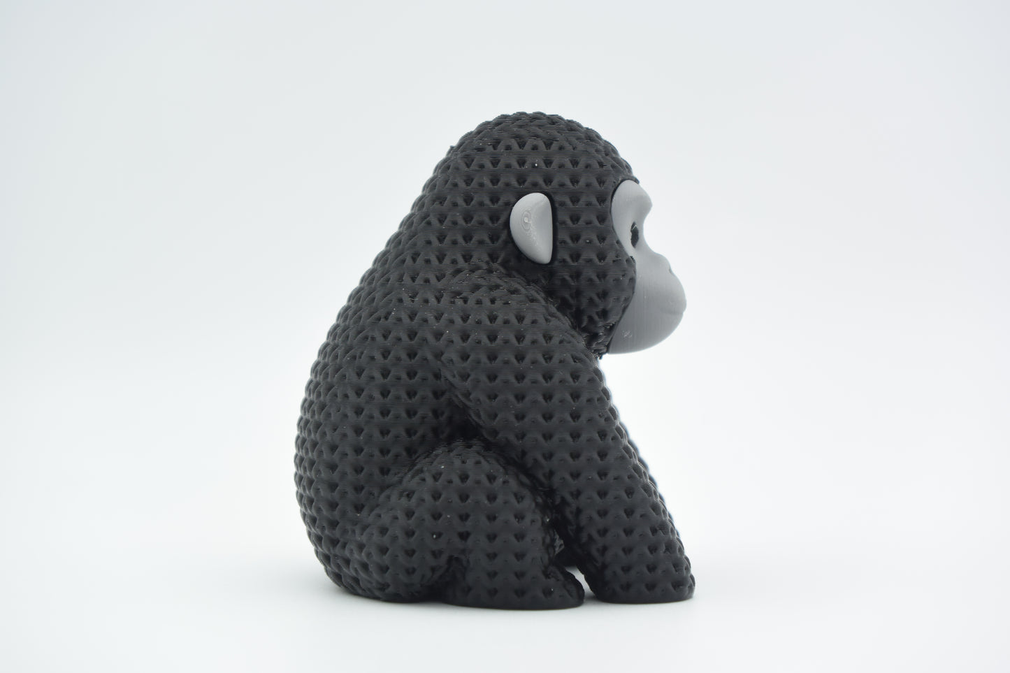 Knitted gorilla decorative figure styled on a wooden shelf beside books and a small plant