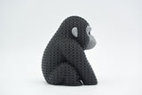 Knitted gorilla decorative figure styled on a wooden shelf beside books and a small plant