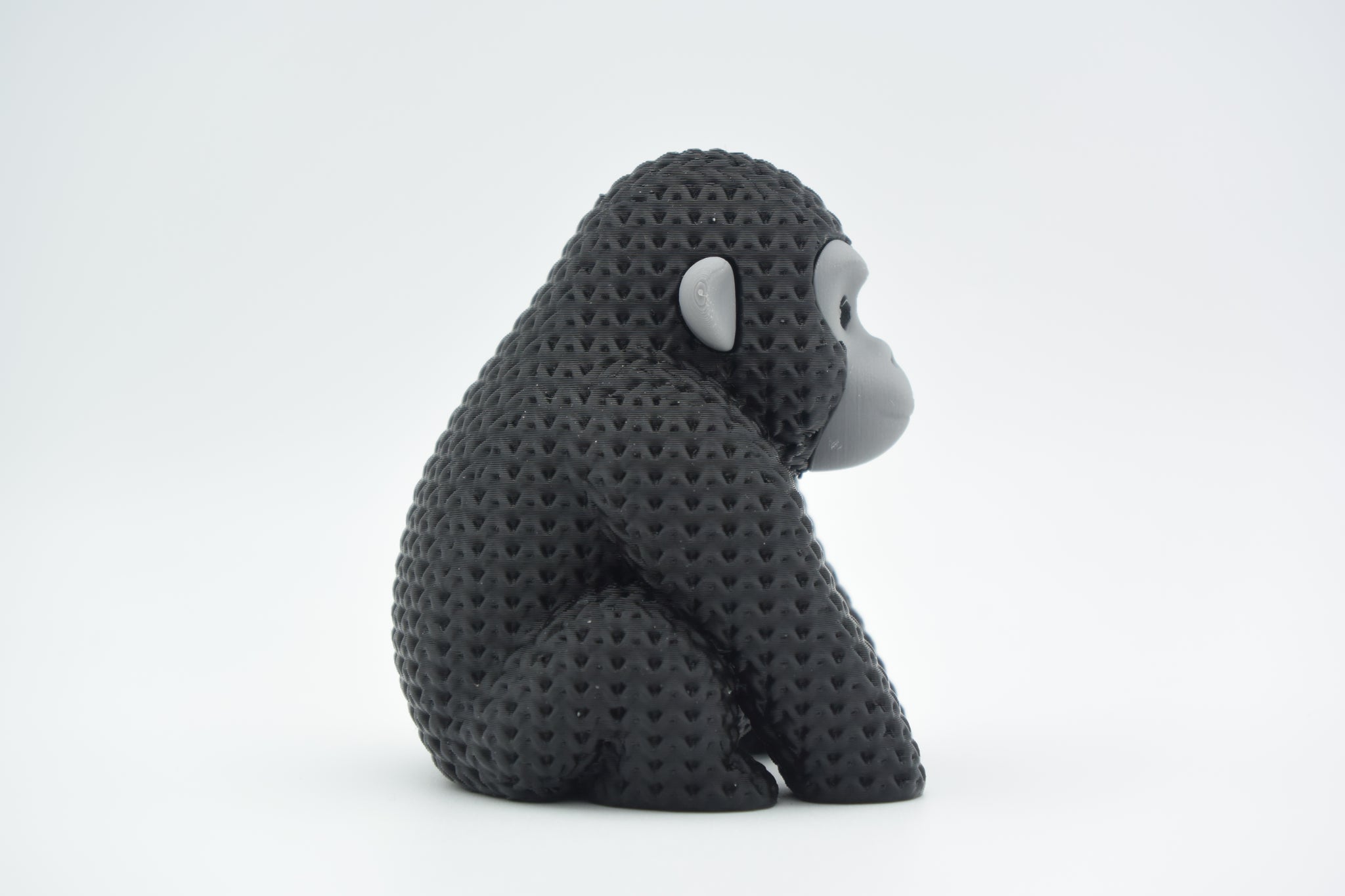 Knitted gorilla decorative figure styled on a wooden shelf beside books and a small plant