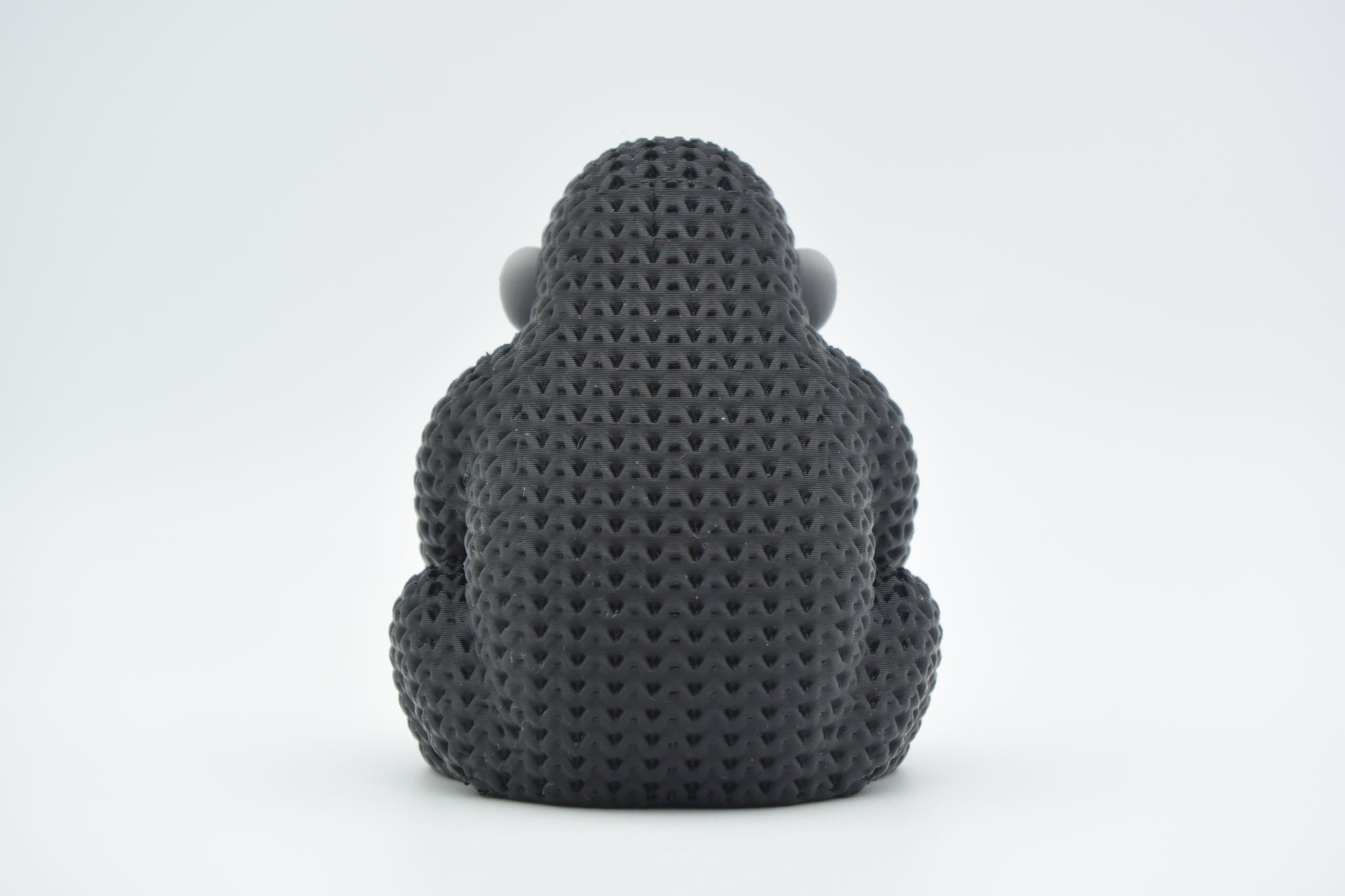 Close-up of a knitted gorilla figurine with detailed crochet-texture surface, photographed on a light background