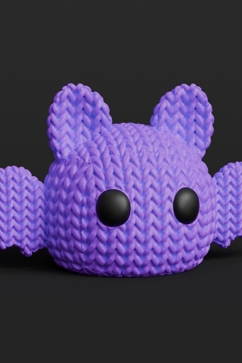 Close-up of a knitted Halloween bat decoration with a soft crochet-look texture and small eyes, shot on a light surface