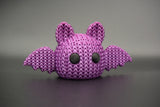Knitted Halloween bat decoration styled on a wooden shelf beside autumn candles and dried leaves in a Scandinavian home