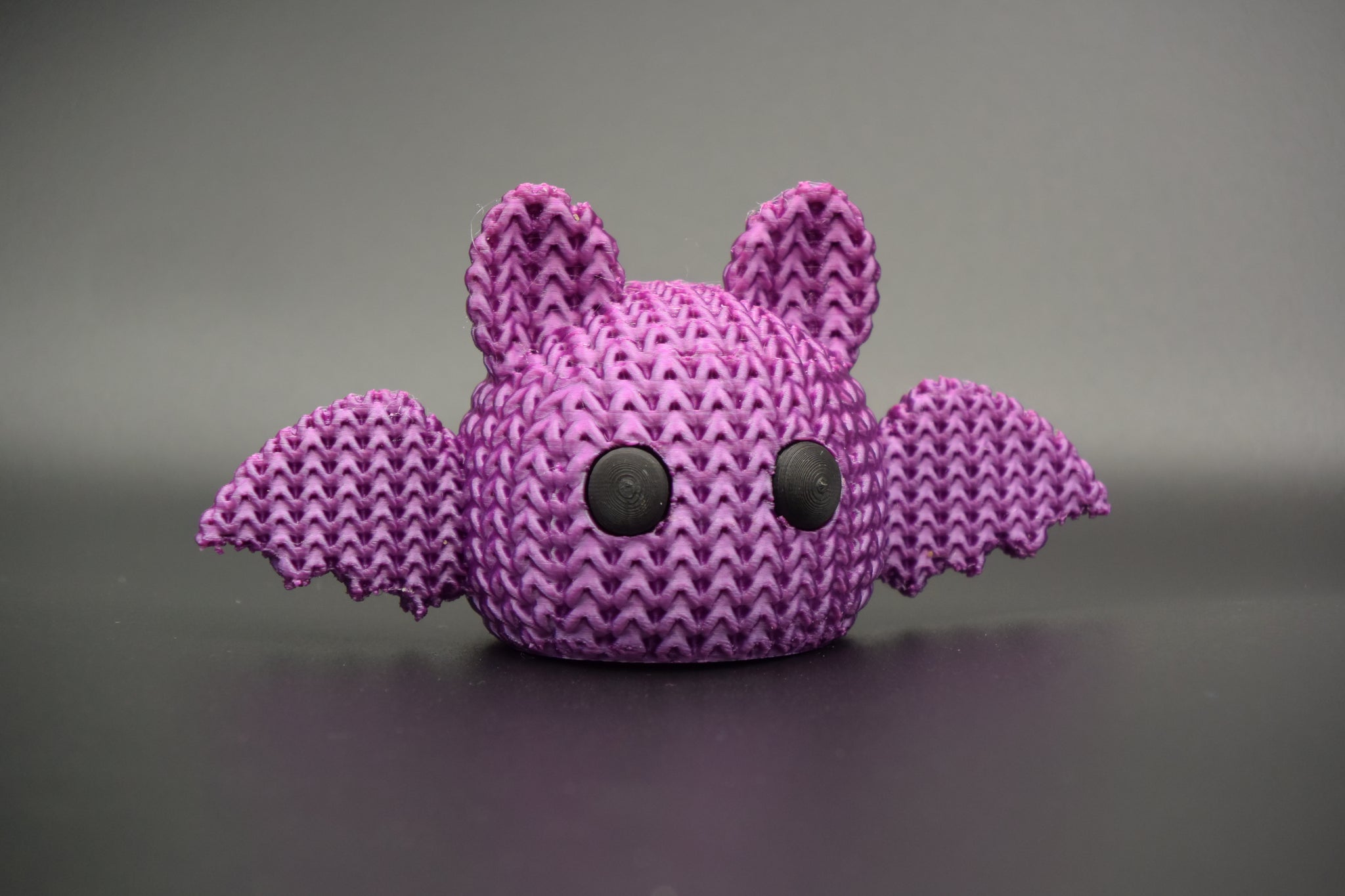 Knitted Halloween bat decoration styled on a wooden shelf beside autumn candles and dried leaves in a Scandinavian home