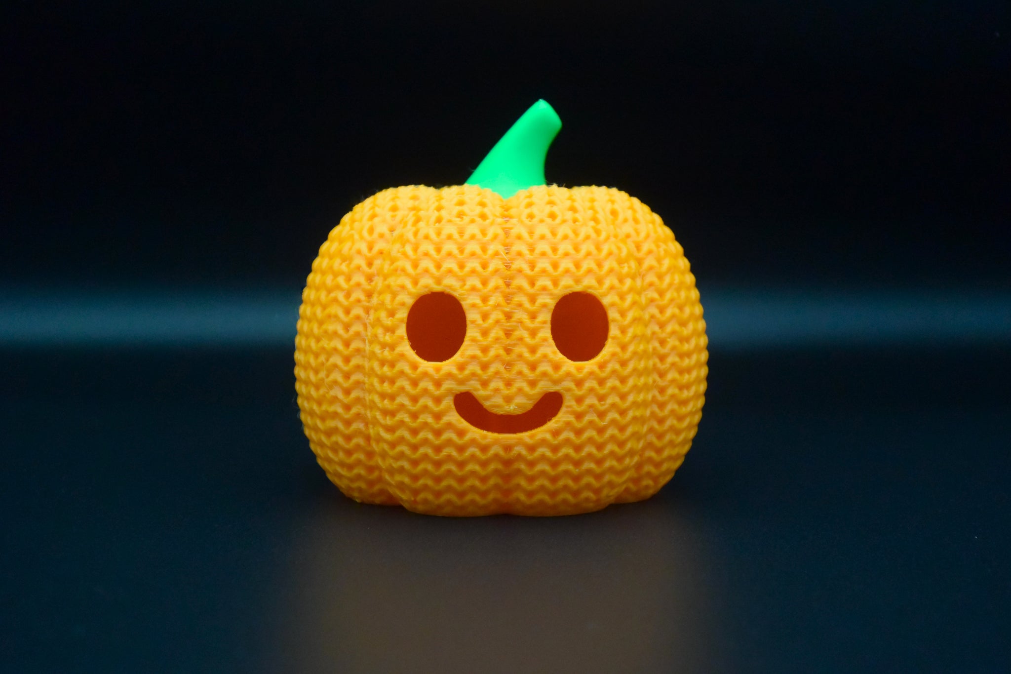 Texture detail of knitted halloween pumpkin surface showing woven pattern and carved facial features