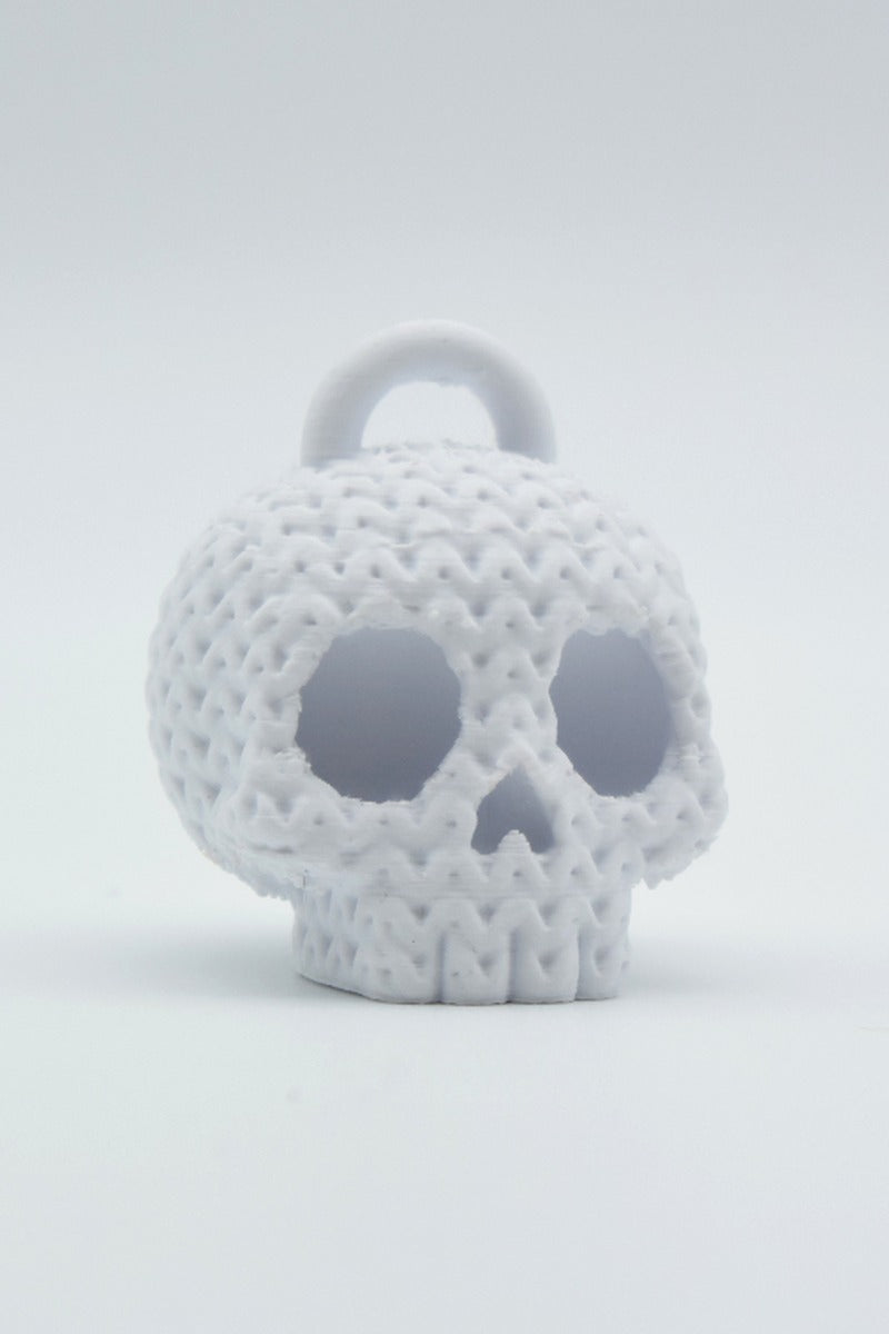 Close-up of a knitted skull keychain with crochet texture detail, shot on a light neutral background