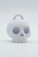 Close-up of a knitted skull keychain with crochet texture detail, shot on a light neutral background