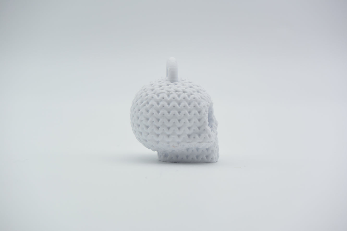 Knitted skull keychain hanging from a bag strap near a front door, styled in a Scandinavian home setting