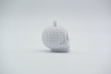 Knitted skull keychain hanging from a bag strap near a front door, styled in a Scandinavian home setting
