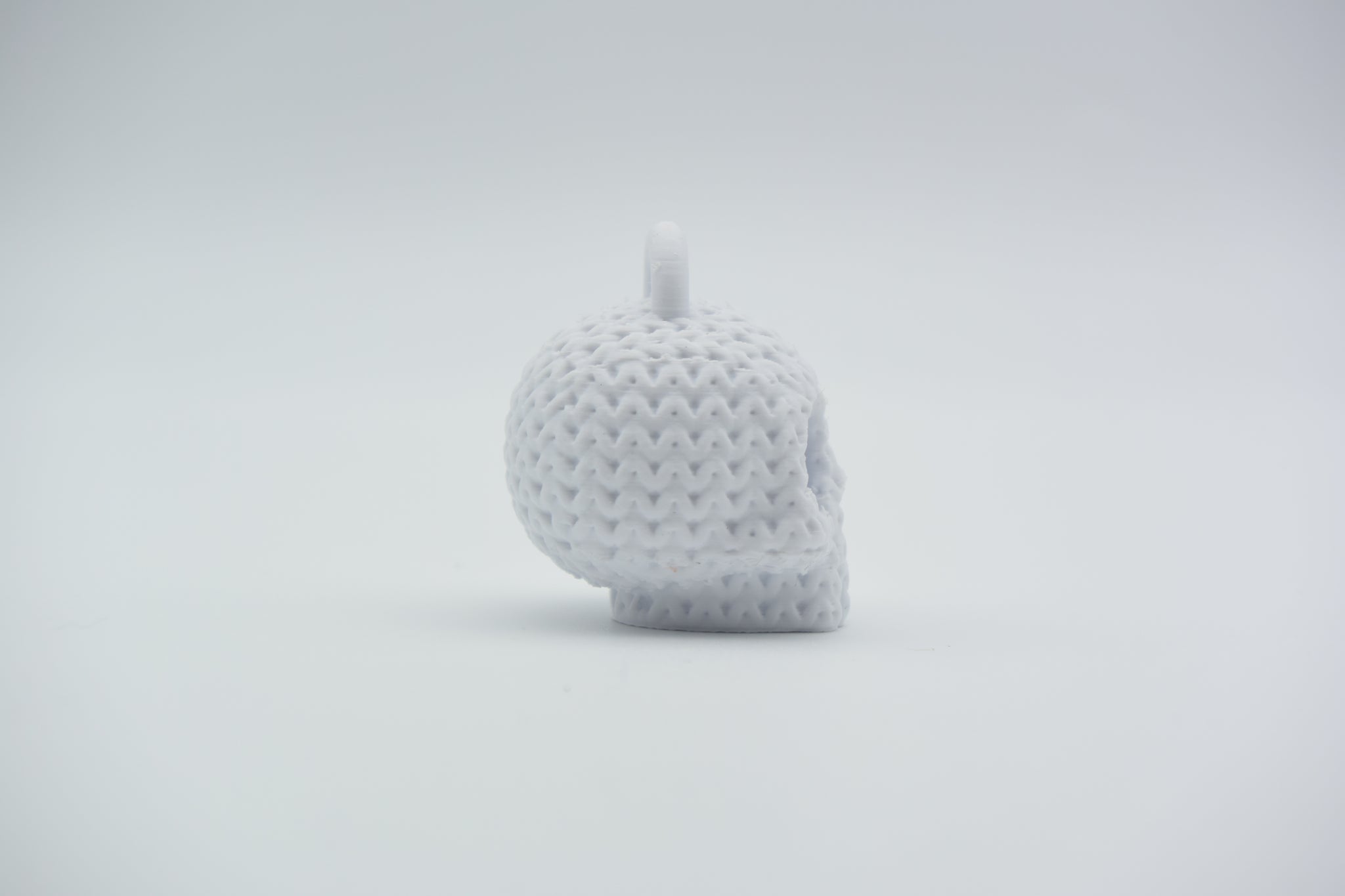 Knitted skull keychain hanging from a bag strap near a front door, styled in a Scandinavian home setting