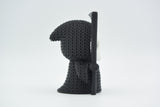 Small knitted grim reaper Halloween decoration styled on a dark wooden shelf beside autumn foliage