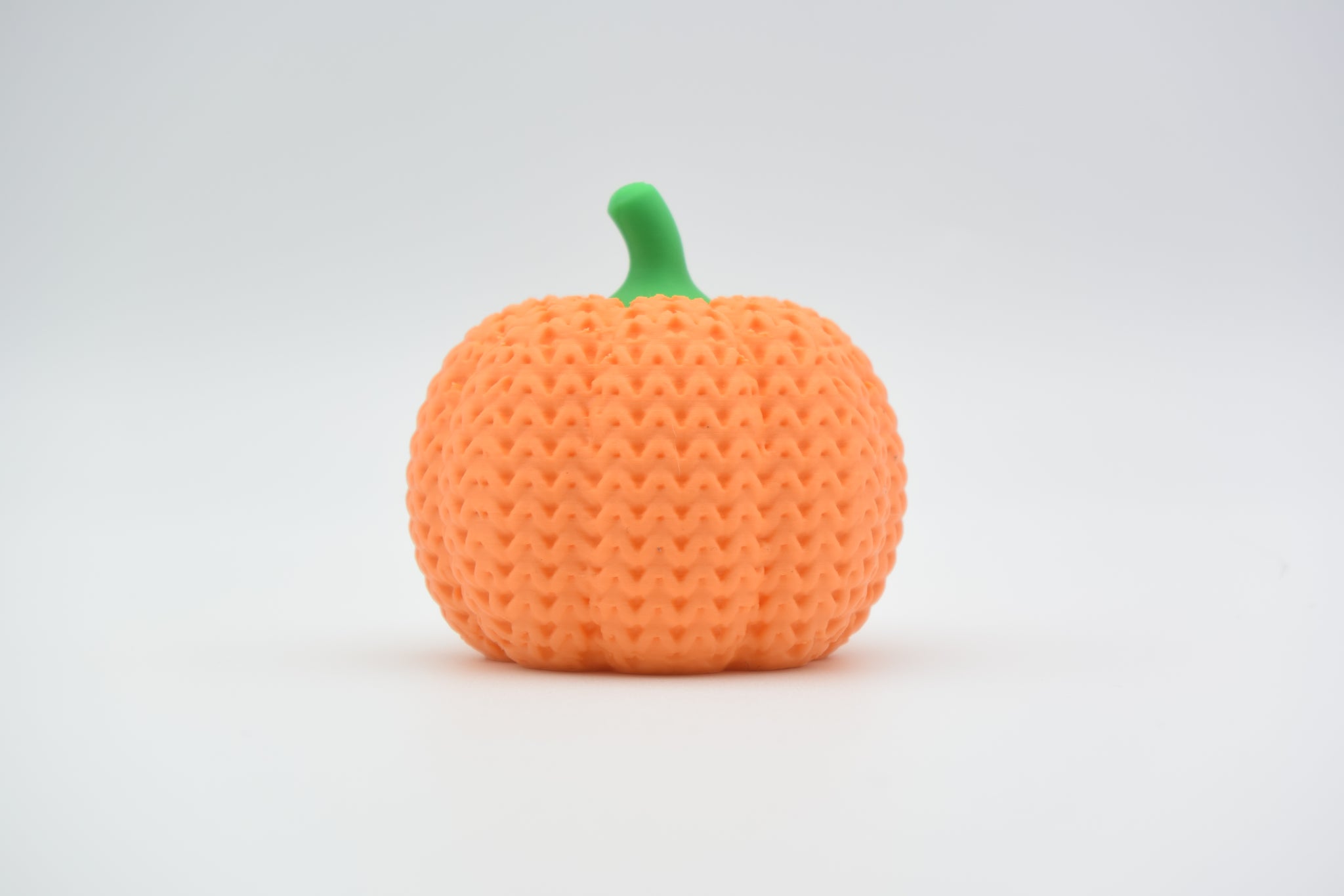 Detail of the knitted surface texture on a crochet pumpkin decoration showing soft ribbed pattern and rounded form