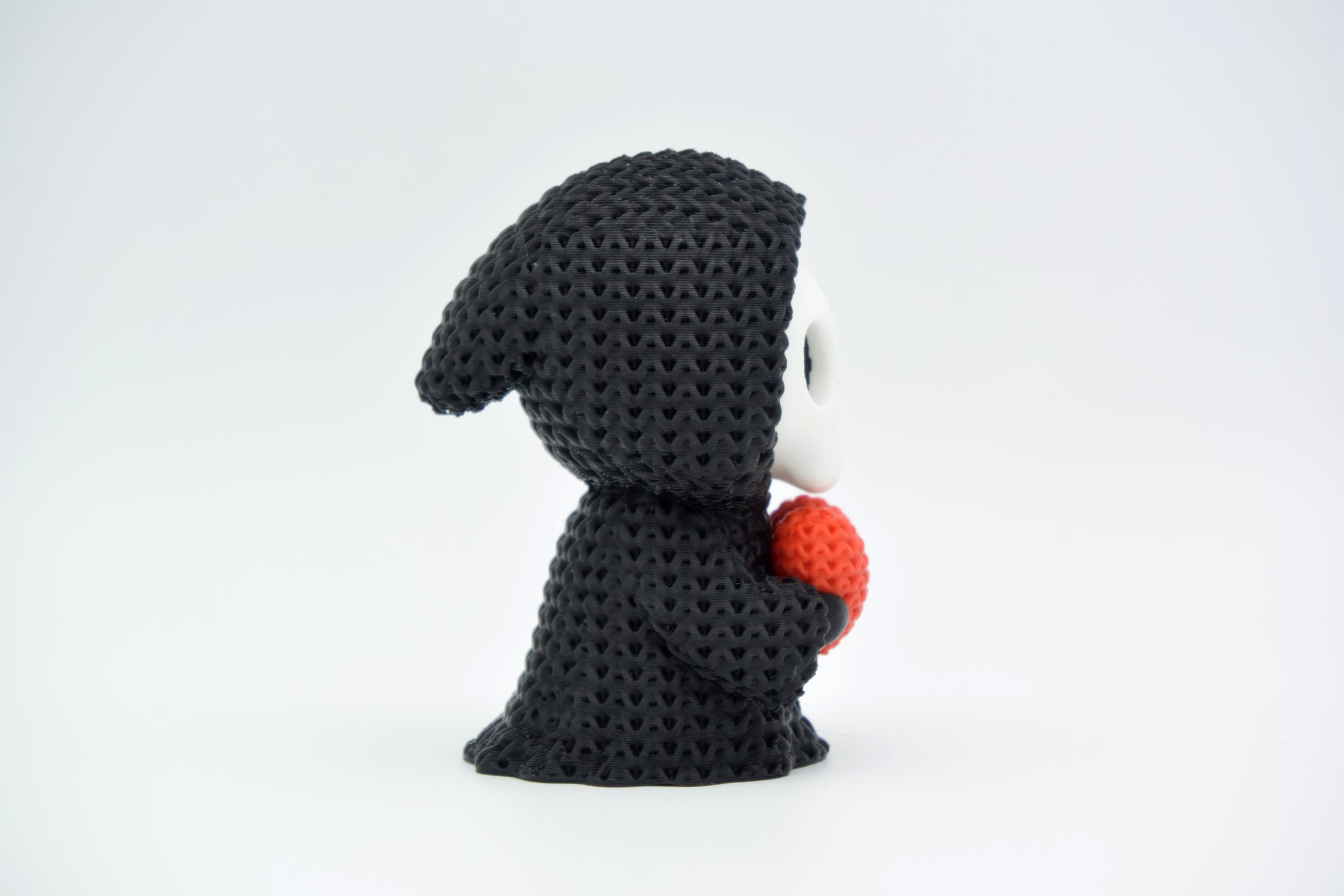 Knitted grim reaper Halloween decoration styled on a wooden shelf beside autumn foliage and a small candle