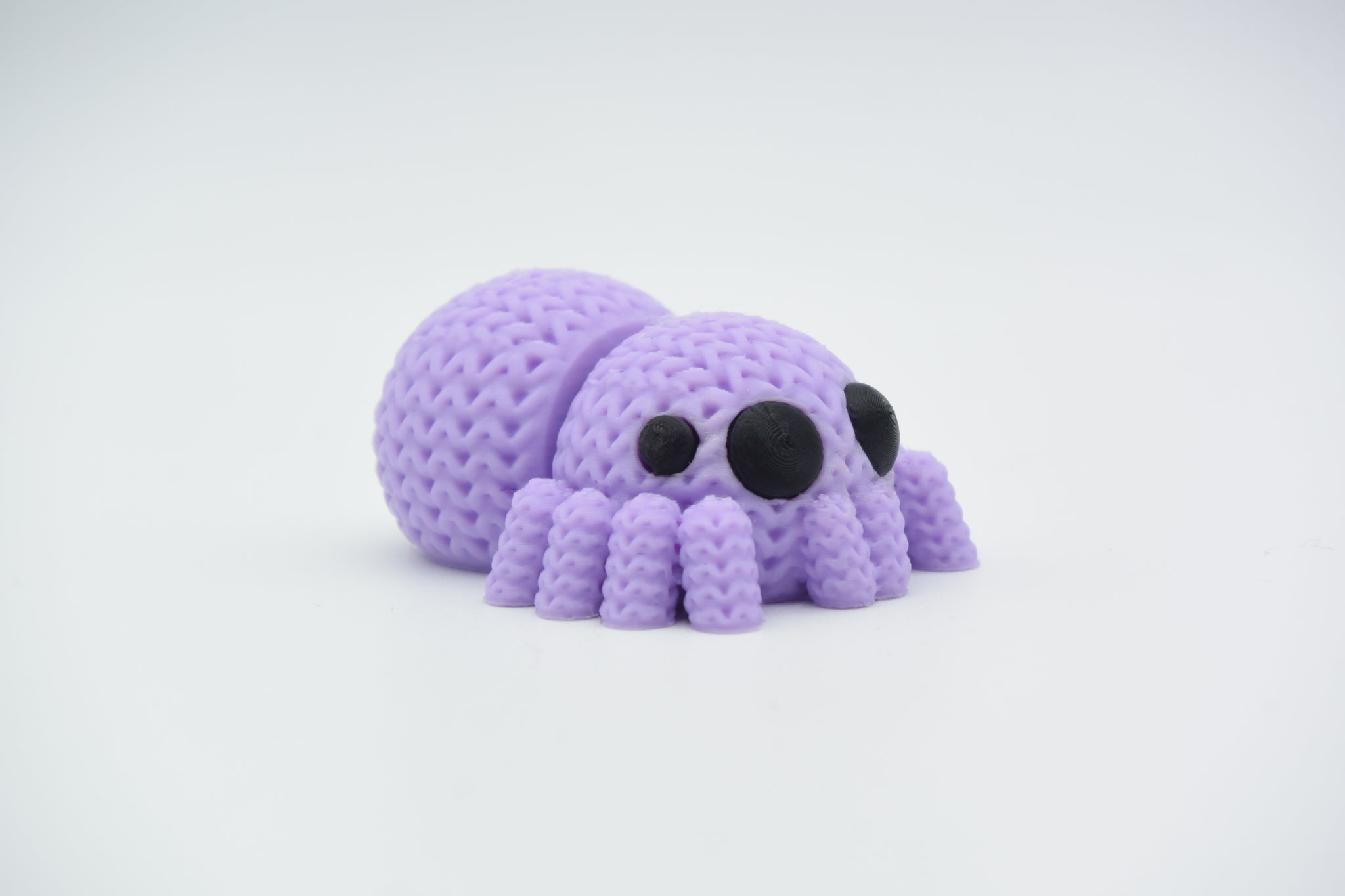 Close-up of a knitted spider decoration with articulated legs and textured crochet-look surface