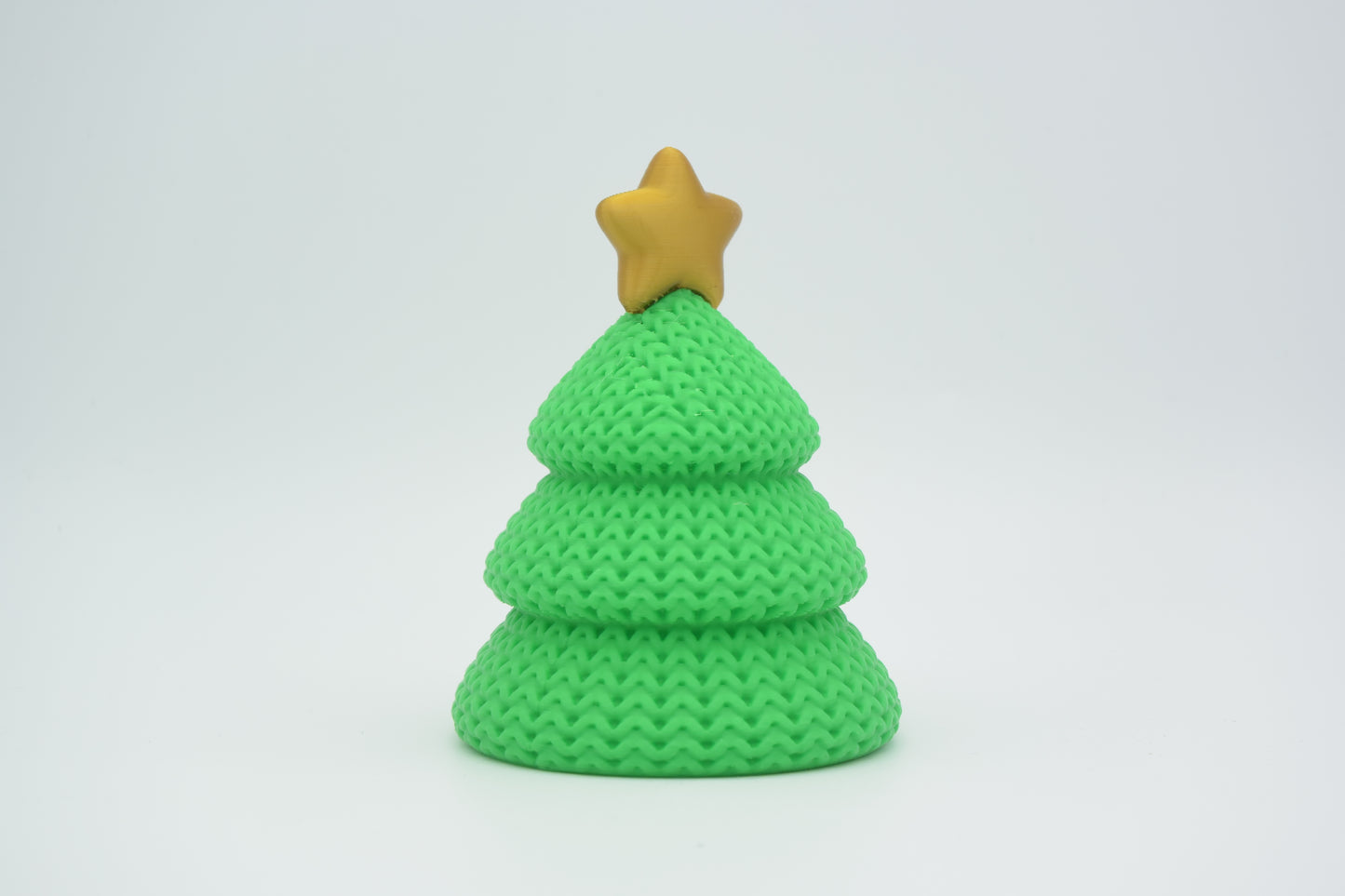 Small knitted Christmas tree styled on a wooden shelf beside candles in a Scandinavian holiday interior
