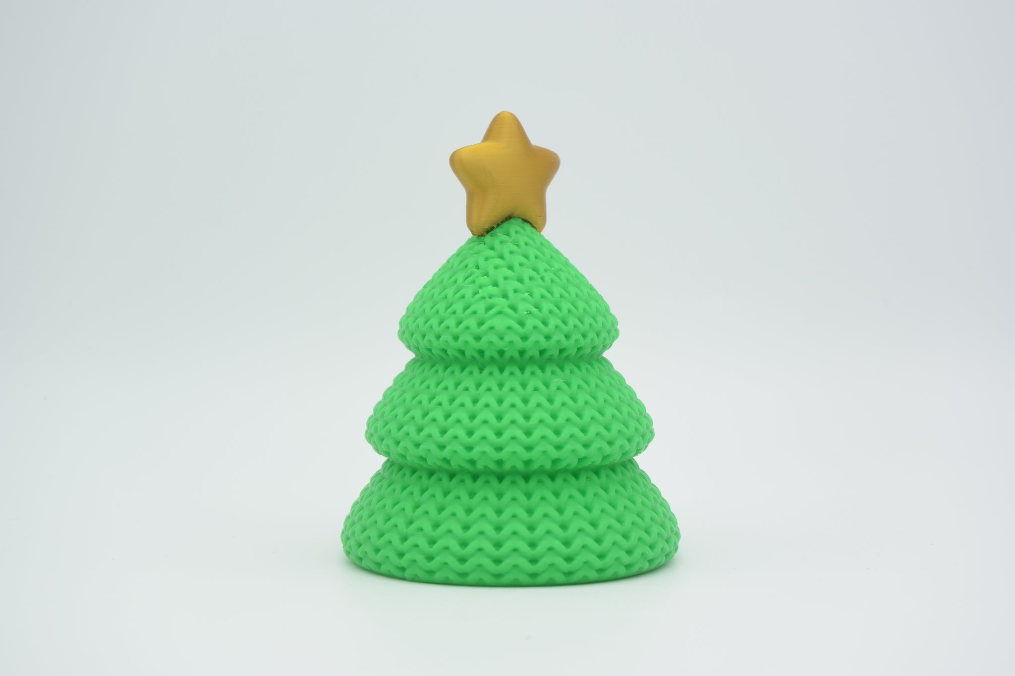 Small knitted Christmas tree styled on a wooden shelf beside candles in a Scandinavian holiday interior