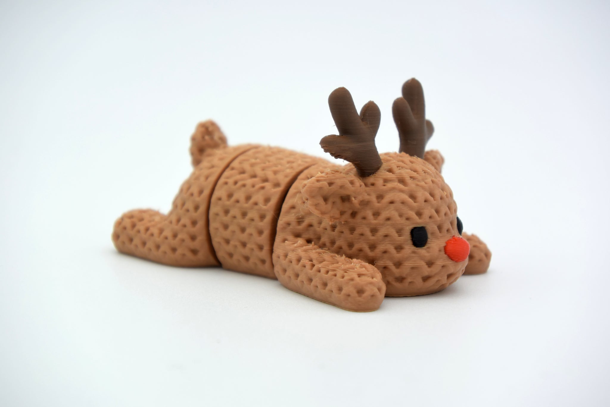 Close-up of a knitted reindeer with textured crochet-look surface and articulated legs, cream coloured