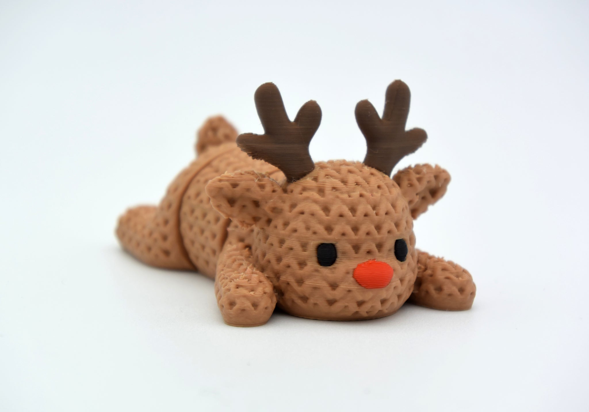 Close-up of a knitted reindeer with textured crochet-look surface and articulated legs, cream coloured
