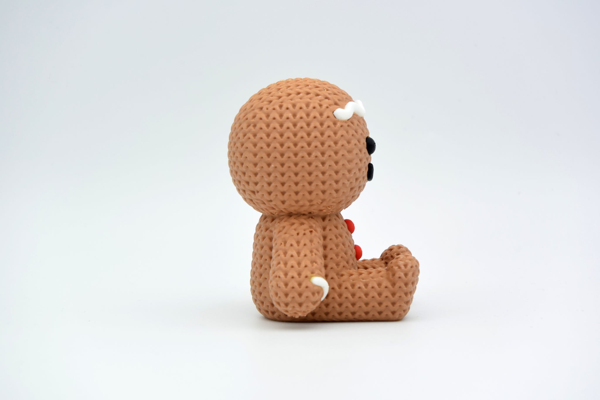 Knitted gingerbread man Christmas decoration styled on a wooden shelf with candles and pine branches