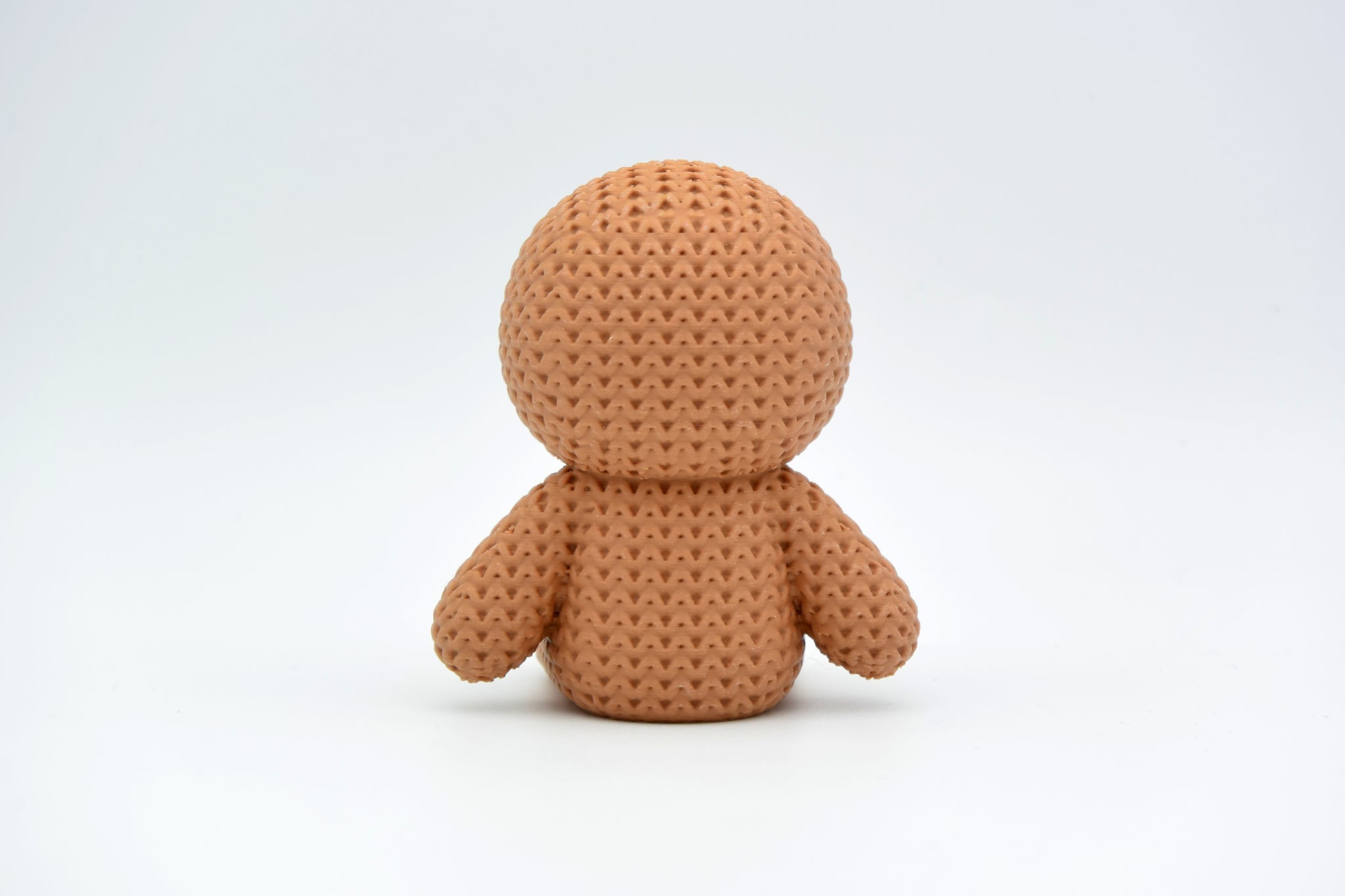 Texture detail of the knitted gingerbread man showing the soft crochet-like surface and icing smile