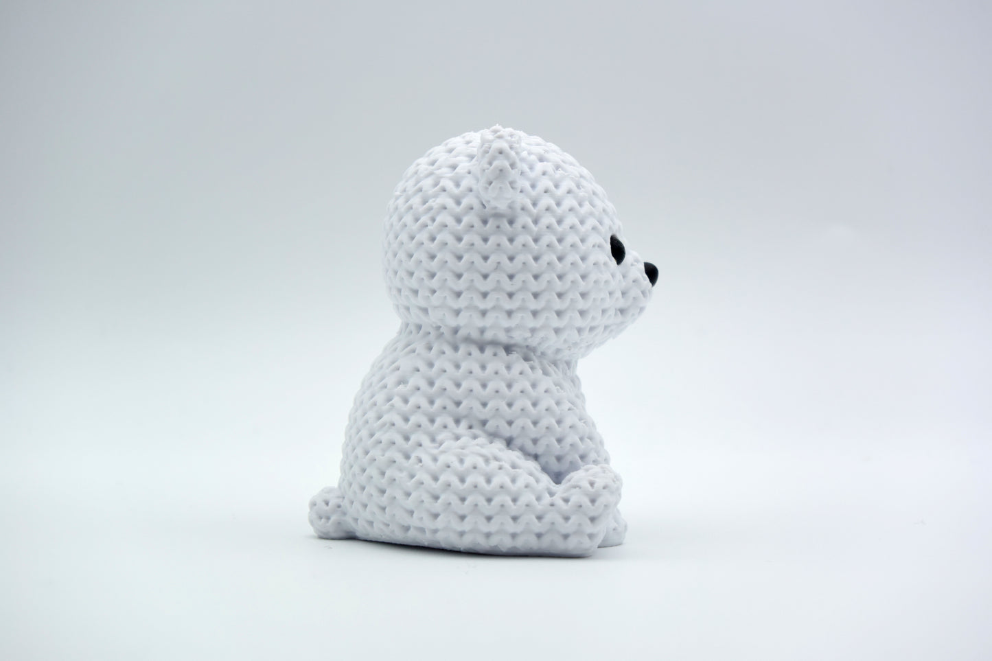 White knitted polar bear decoration placed on a wooden shelf beside winter greenery in a Scandinavian home