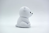 White knitted polar bear decoration placed on a wooden shelf beside winter greenery in a Scandinavian home