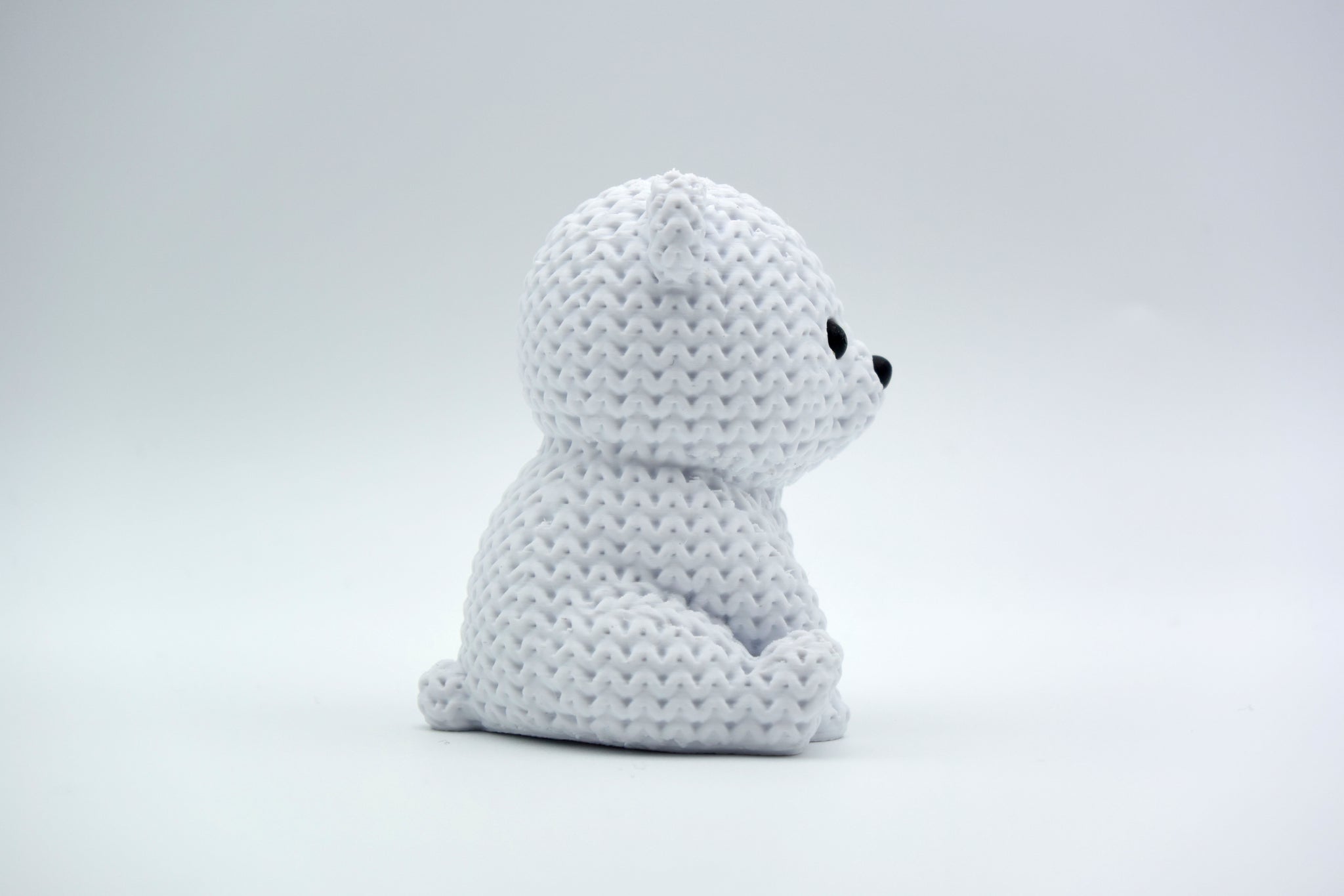 White knitted polar bear decoration placed on a wooden shelf beside winter greenery in a Scandinavian home