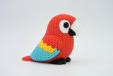 Close-up of a knitted scarlet macaw parrot figurine with textured red, blue and yellow surface detail