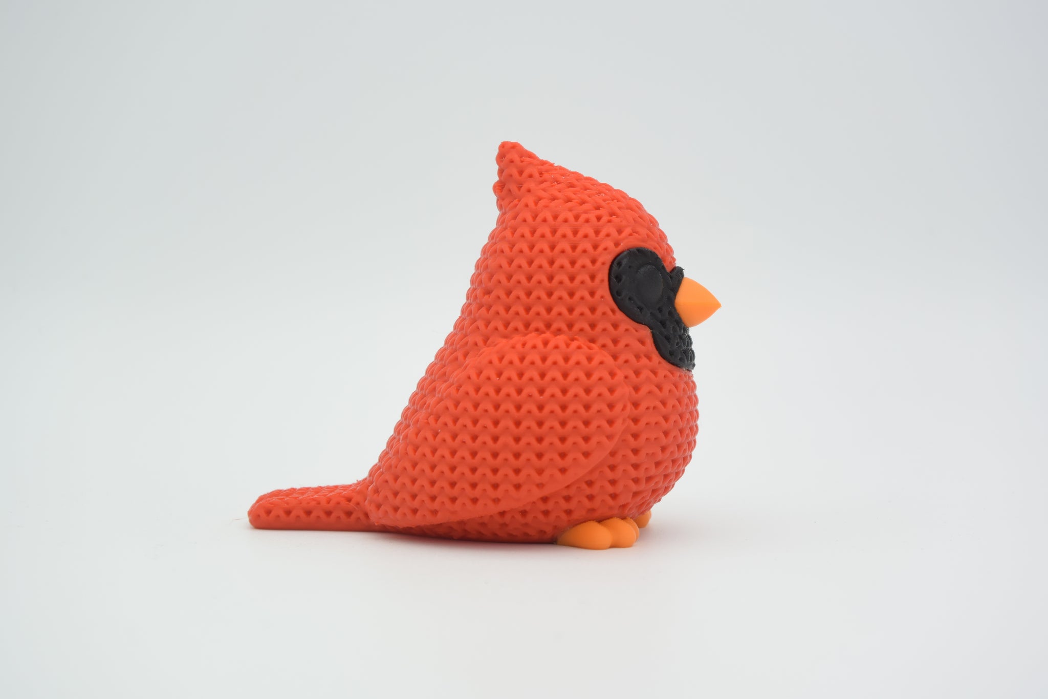 Texture detail of the cardinal bird figure showing the fine knitted surface pattern across the red body
