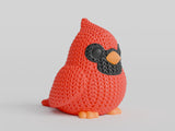 Close-up of a knitted cardinal bird figure with red crochet-look texture and dark facial markings, 49 DKK