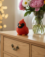 Close-up of a knitted cardinal bird figure with red crochet-look texture and dark facial markings, 49 DKK