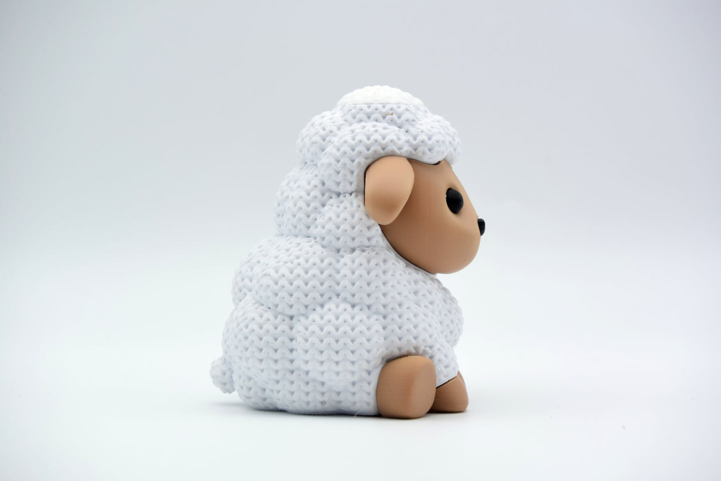 Knitted sheep decoration styled on a wooden shelf beside a small plant and neutral home accessories