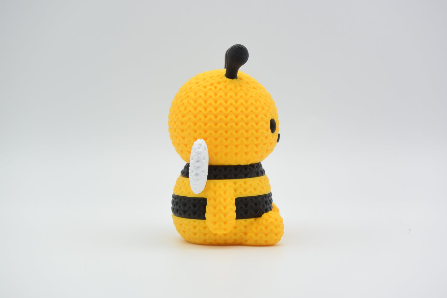 Knitted bee decoration placed on a wooden shelf next to a small potted plant in a bright Scandinavian interior