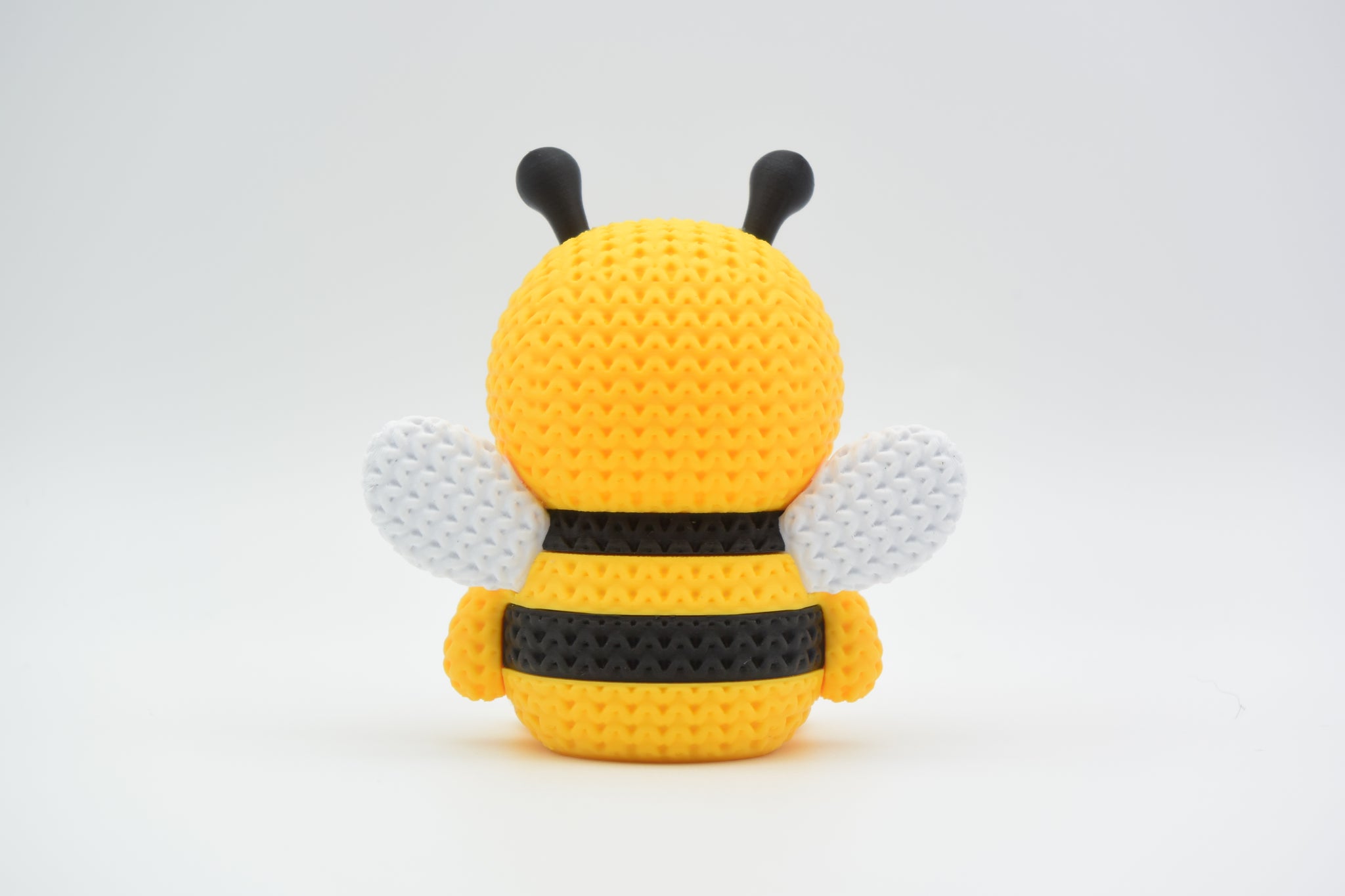 Detailed view of the crochet-look surface texture on a decorative bee figure showing stripe pattern and woven appearance