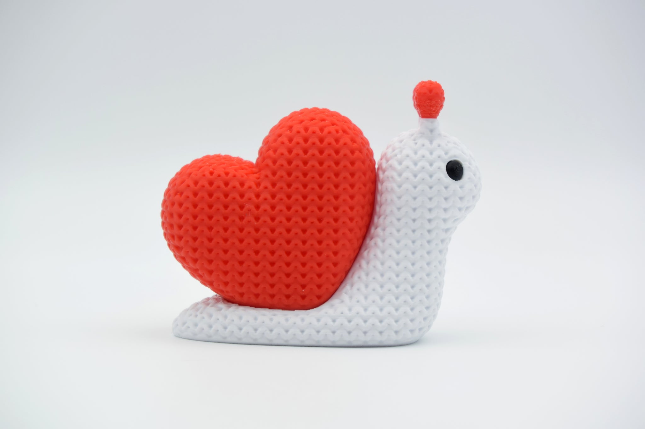 Knitted snail decoration placed on a wooden shelf in a warm Scandinavian home setting