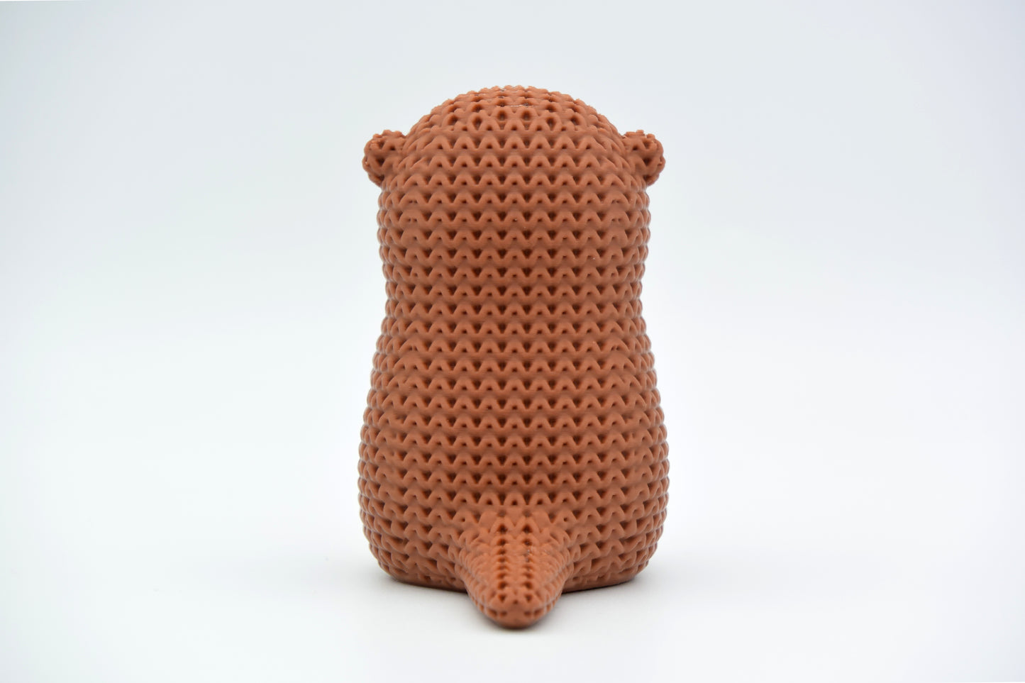 Macro detail of the looped knitted texture on a crochet otter figurine in warm neutral tones