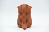 Macro detail of the looped knitted texture on a crochet otter figurine in warm neutral tones