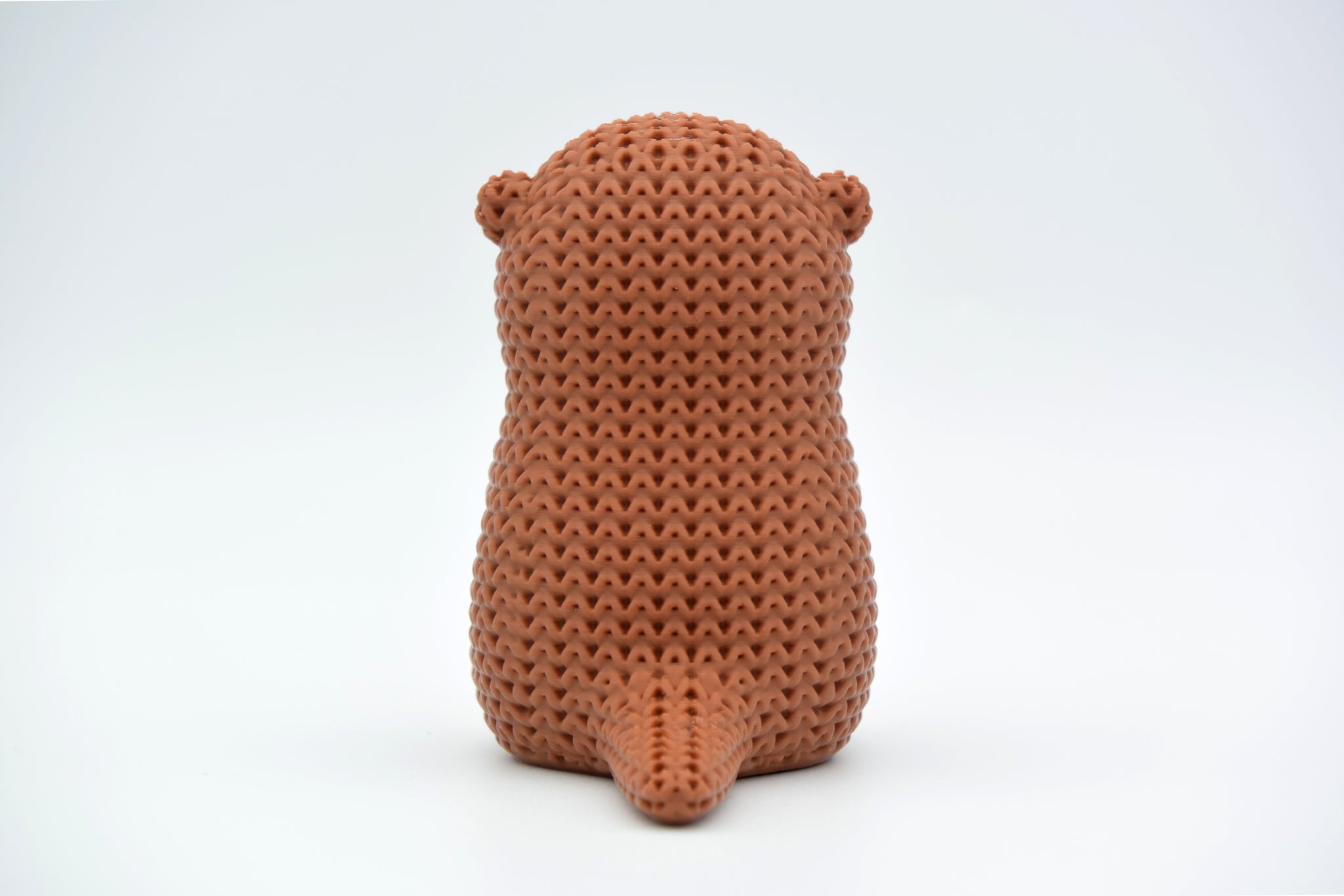 Macro detail of the looped knitted texture on a crochet otter figurine in warm neutral tones