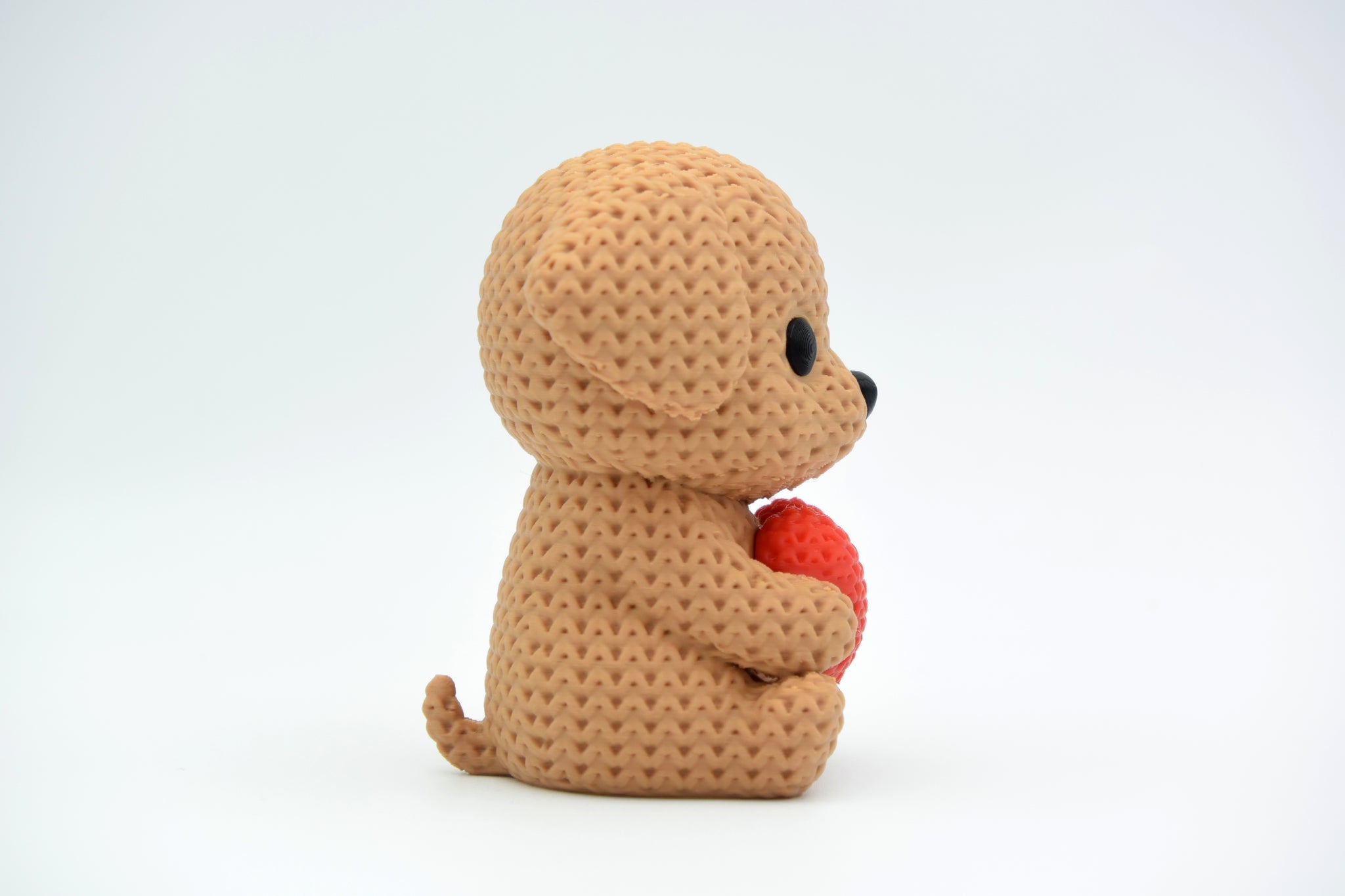 Small knitted-look dog with heart displayed on a wooden shelf beside dried flowers in a cosy home setting