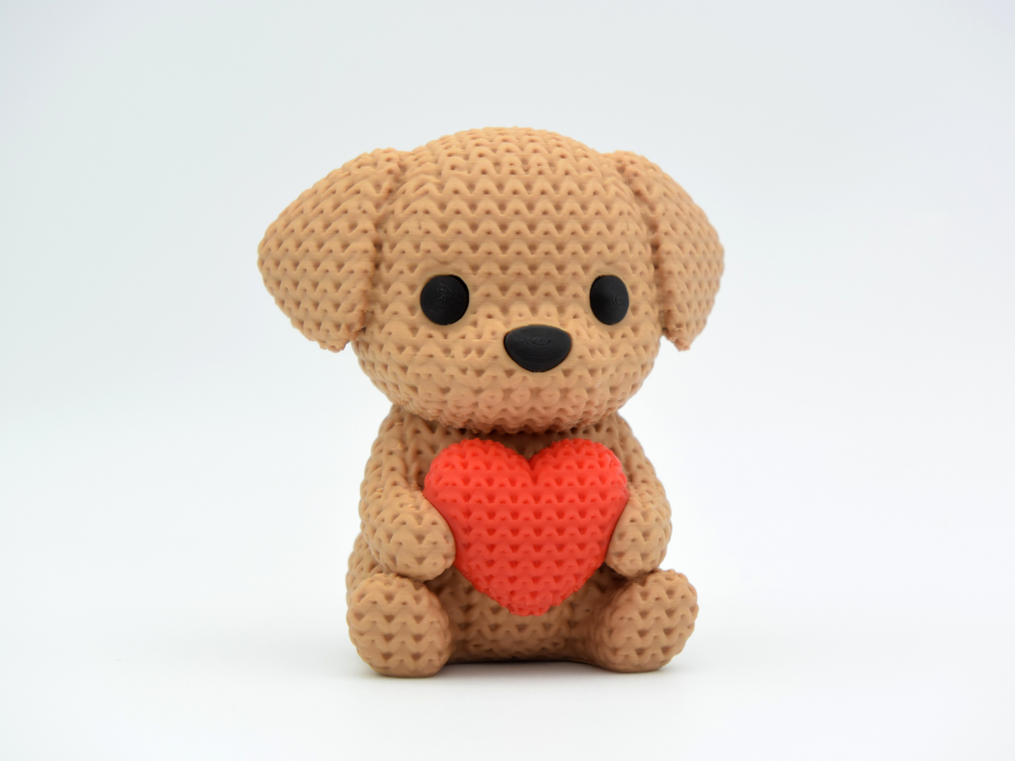 Close-up of a crochet dog ornament holding a small heart, showing soft looping texture across the body
