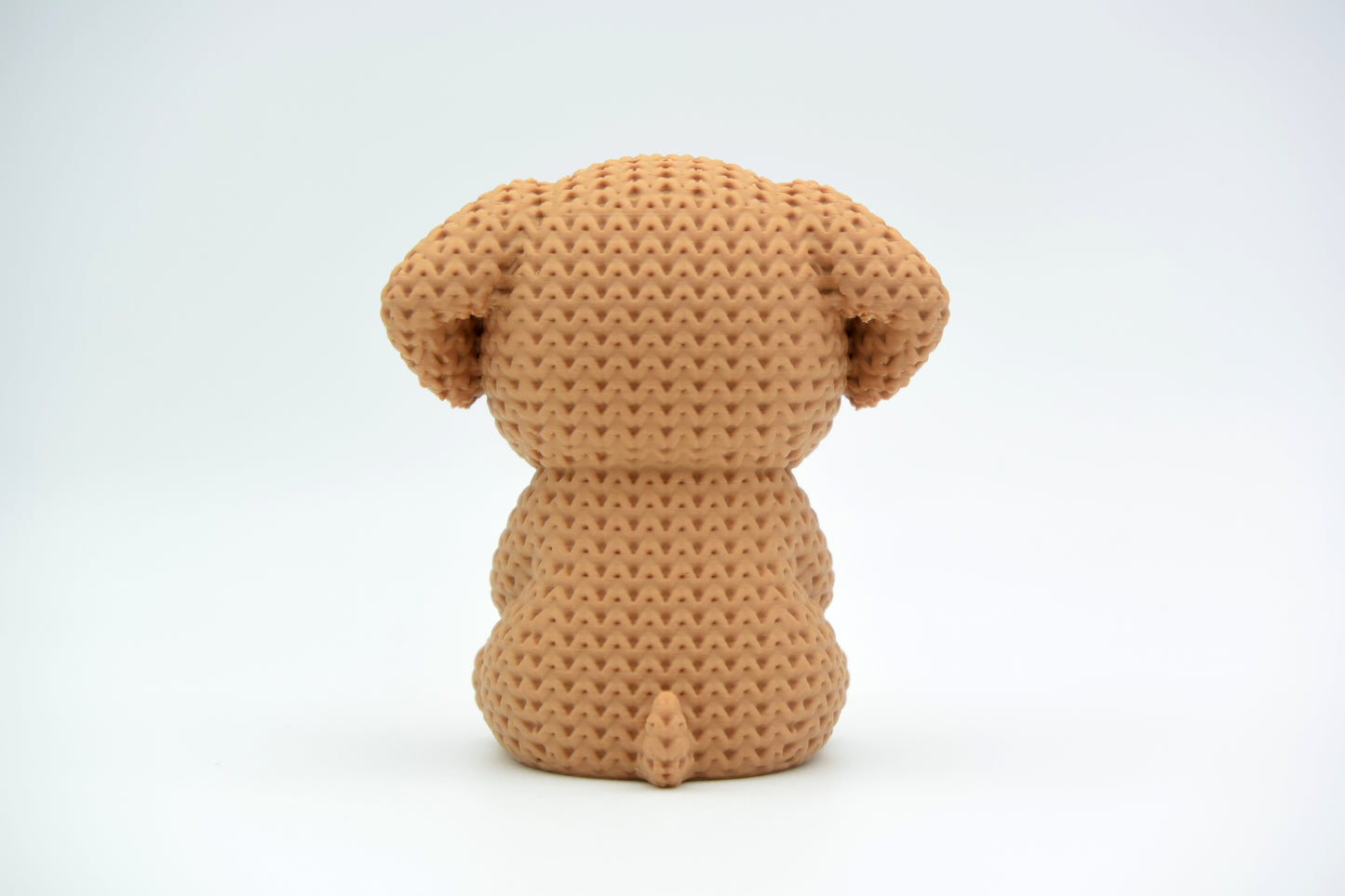Close-up of a crochet dog ornament holding a small heart, showing soft looping texture across the body