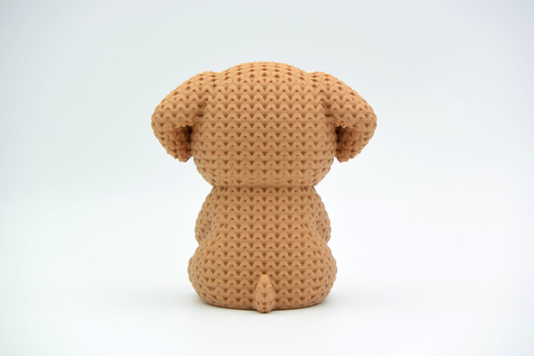 Close-up of a crochet dog ornament holding a small heart, showing soft looping texture across the body