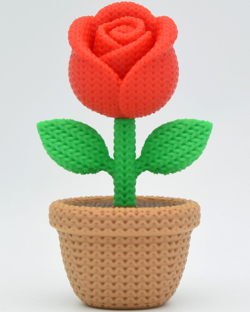Close-up of a decorative knitted rose with soft petal texture and warm red tones
