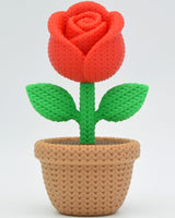 Close-up of a decorative knitted rose with soft petal texture and warm red tones