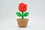 Knitted rose placed on a light wooden shelf next to a candle in a Scandinavian home setting