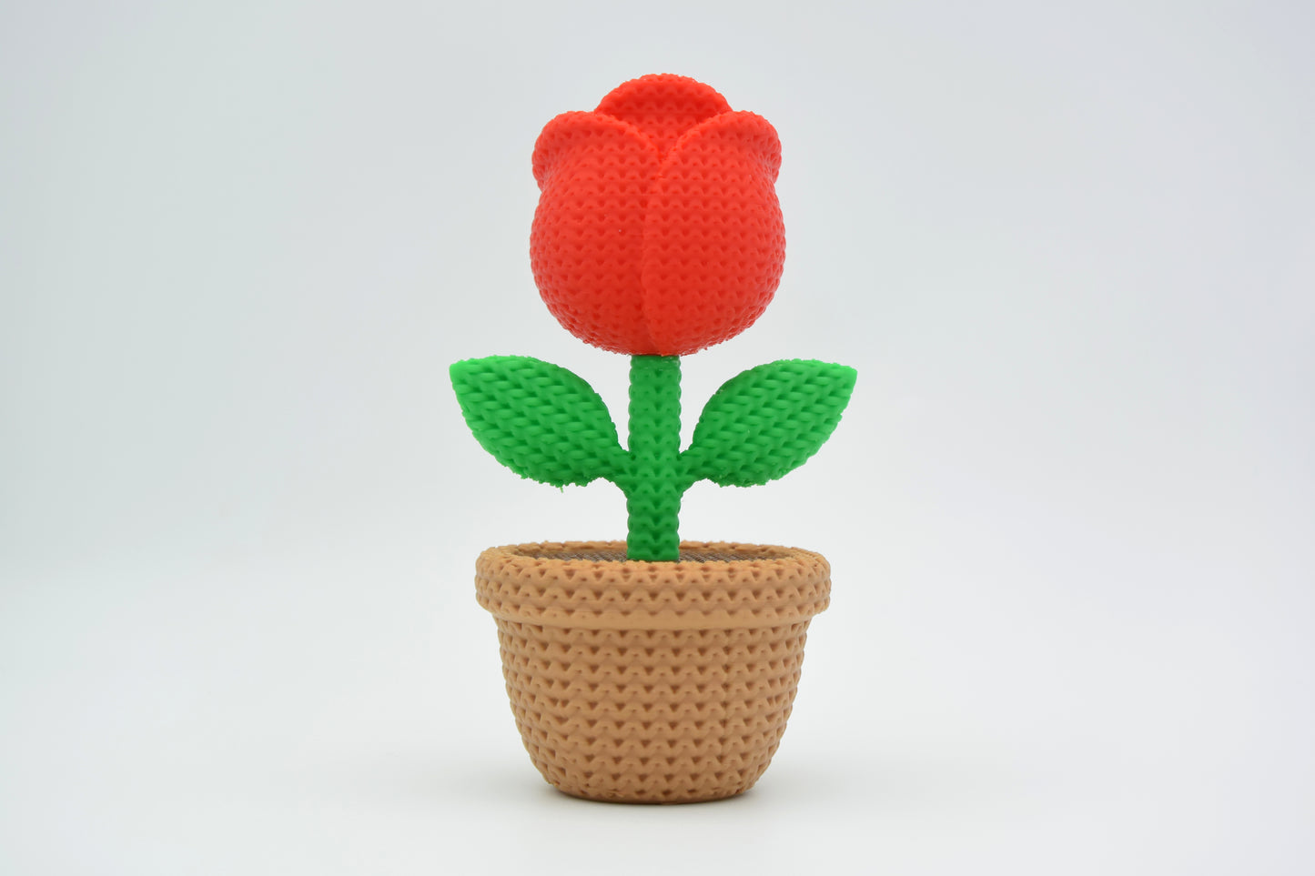 Close-up of a decorative knitted rose with soft petal texture and warm red tones