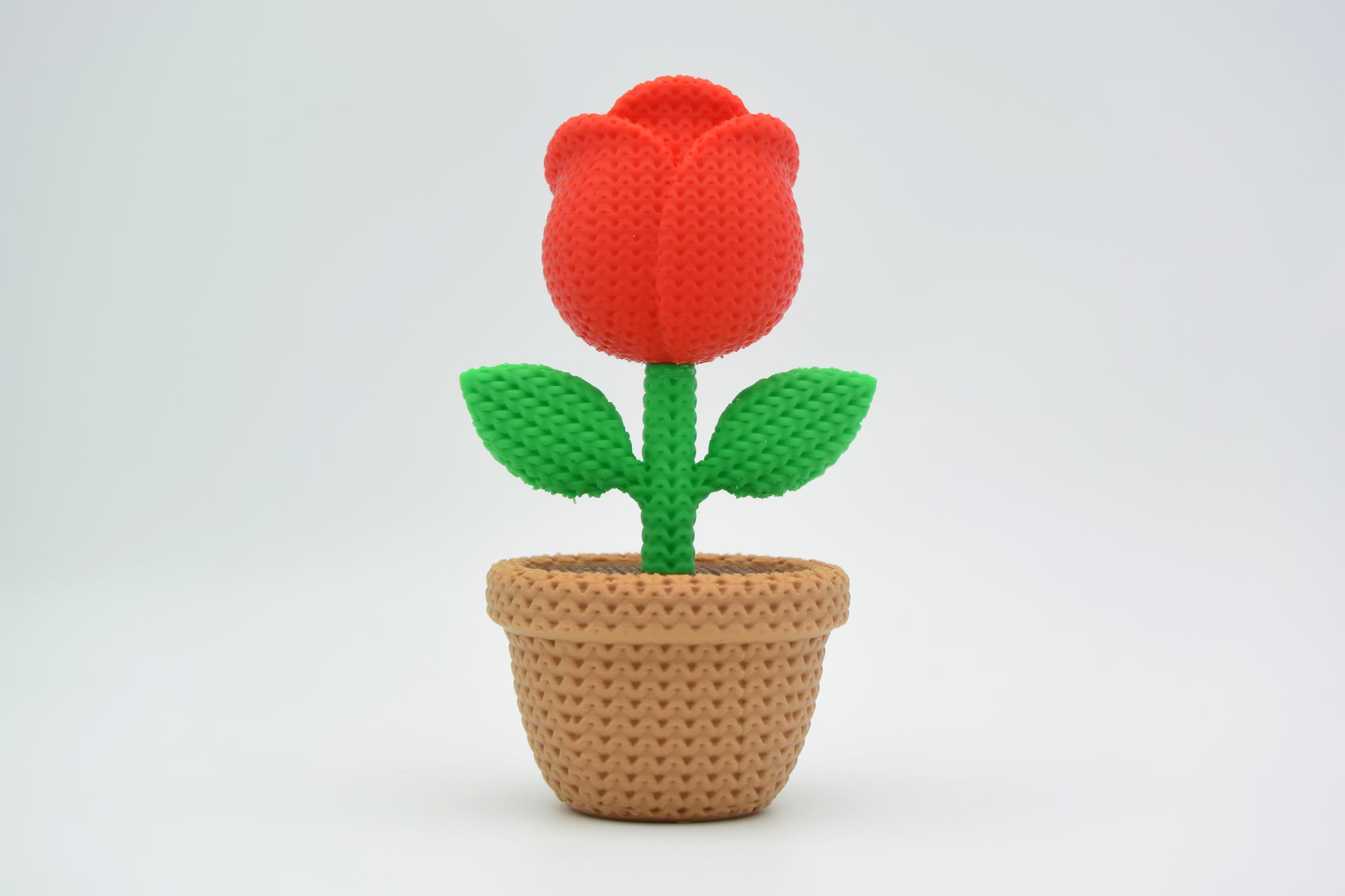 Close-up of a decorative knitted rose with soft petal texture and warm red tones