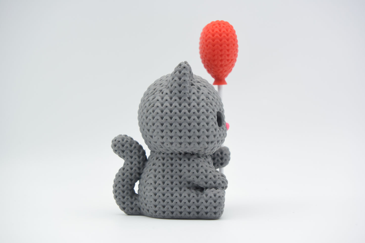 Knitted cat with heart balloon displayed on a light wooden shelf in a Scandinavian living room setting
